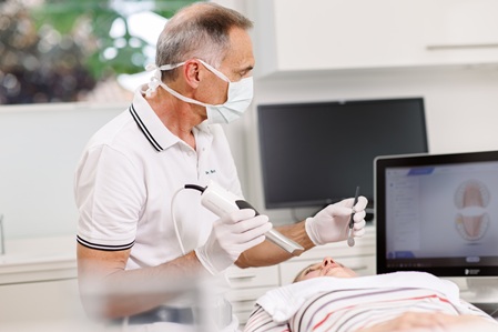 Dr. Schmid während einer Behandlung mit einem modernen 3D Scanner für digitale Abdrücke